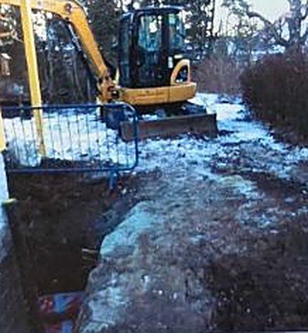Gravemaskin på en snødekt tomt